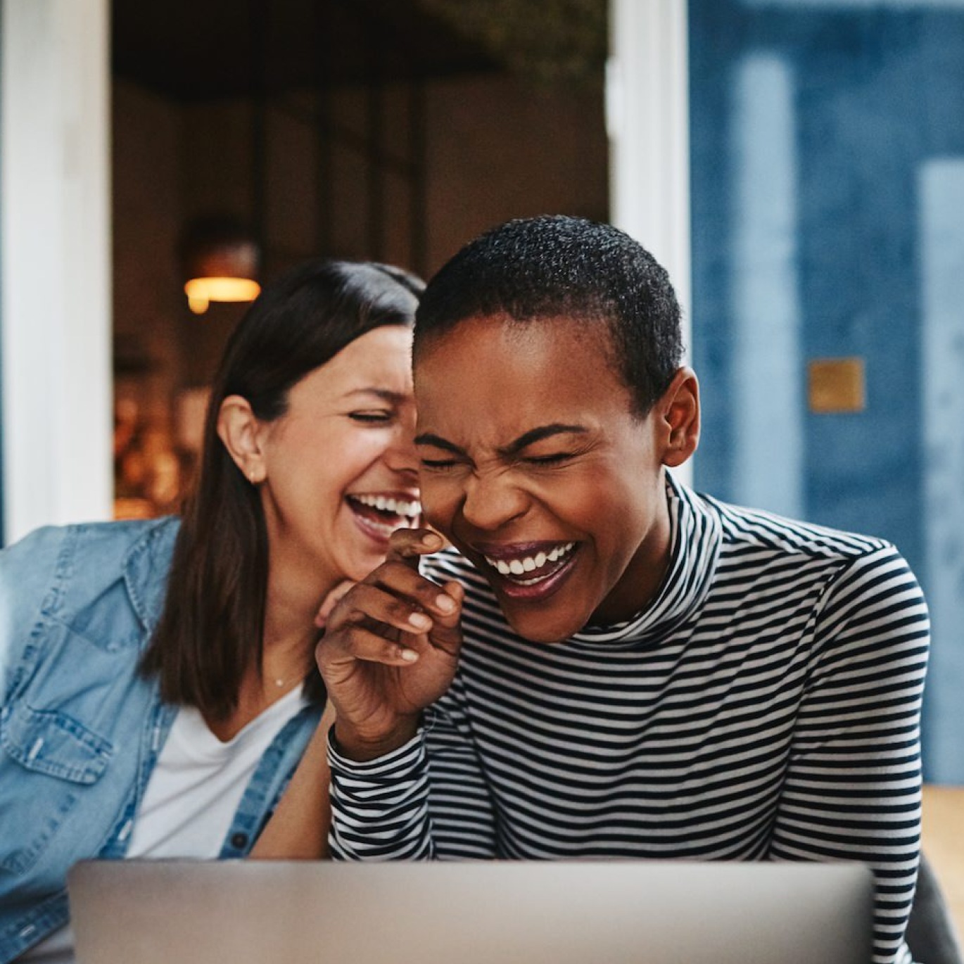 two women laughing in front of a computer